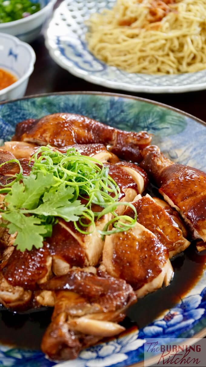 Whole chopped soy sauce chicken ready to serve, with chilli sauce, spring onions and noodles