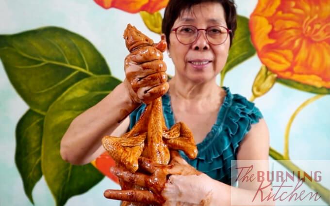 Lady holding up marinate chicken with wings folded backwards